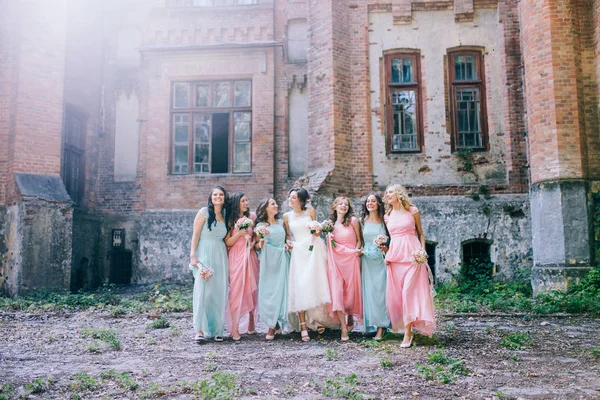 tender bride with smiling bridesmaids dressed in long elegant dresses