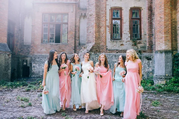 tender bride with smiling bridesmaids dressed in long elegant dresses