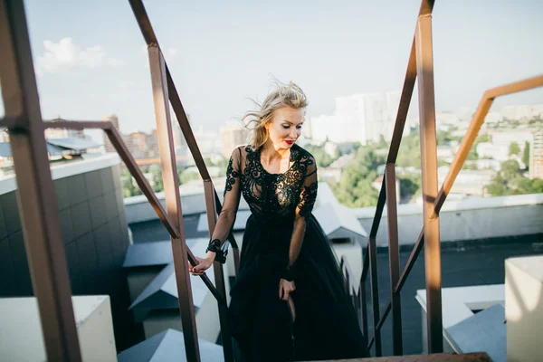 Attractive blonde  in black dress posing on roof
