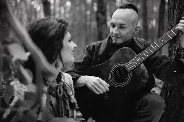 Handsome guy playing  the guitar for his beloved girl in the forest