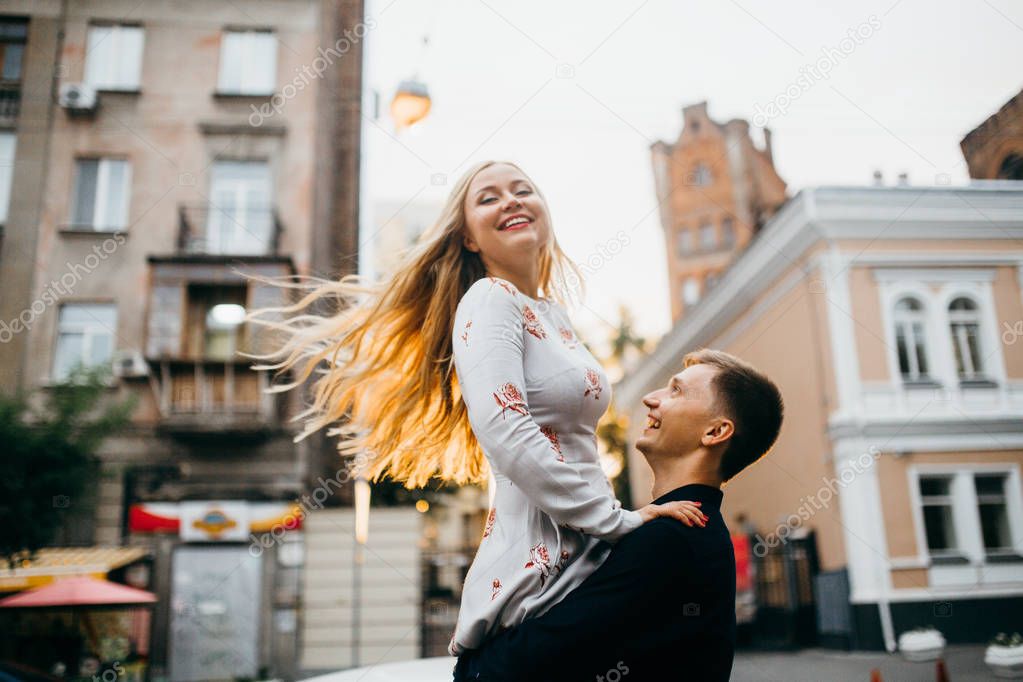 young beautiful couple posing   in  city. Man holding woman