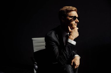 Güneş gözlüklü genç yakışıklı adam poz veriyor.