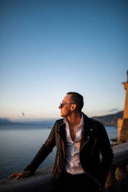 Genç adam deniz kenarında poz veriyor.