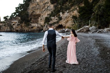 Deniz kenarında yürüyen mutlu, genç bir çift