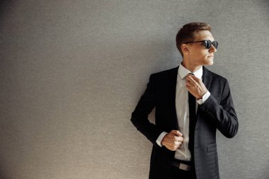 Güneş gözlüklü genç yakışıklı adam poz veriyor.