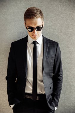 Güneş gözlüklü genç yakışıklı adam poz veriyor.