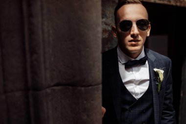 Güneş gözlüklü genç yakışıklı adam poz veriyor.