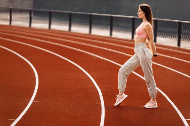 Stadyumda egzersiz yapan genç ve formda bir kadın. 