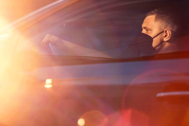 Arabada maske takan genç bir adam.