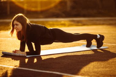 Park yerinde egzersiz yapan genç, zinde bir kadın.