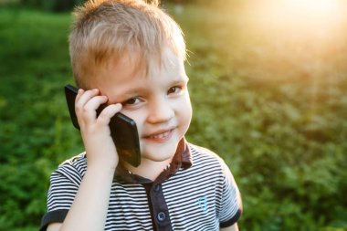 Telefon ve gülümsüyor yaz bahçede tutan küçük şirin çocuk