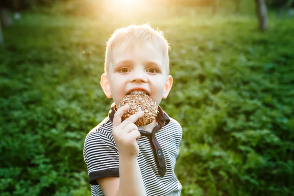 Child Eating Cookie On green nature Background.