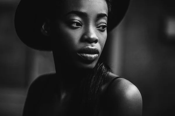 Portrait of African female model in fashion hat posing outdoor on grey background.