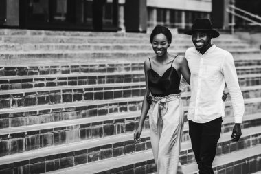 Güzel Afrikalı çift gülümseyen ve açık havada, tek renkli yürüyüş sarılma