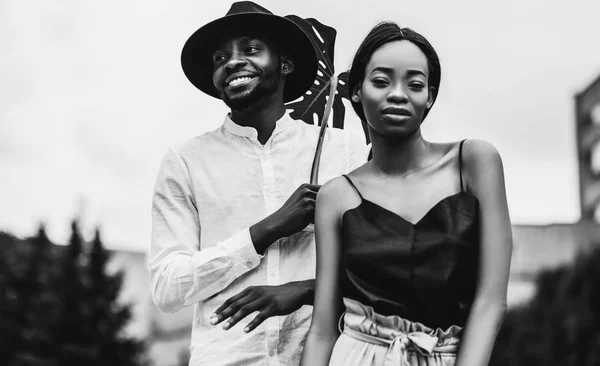 Lovely african newlyweds smiling posing outdoors with monstera leaf, monochrome portrait