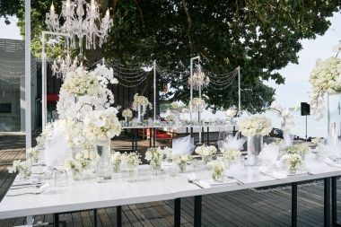 The wedding venue for reception dinner table decorated with white orchids, white roses, flowers, floral, white and clean theme on the Beach clipart