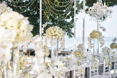 Resepsiyon akşam yemeği masa düğün mekanı dekore edilmiş beyaz orkide, beyaz güller, çiçek, çiçek, beyaz ve temiz tema sahilde