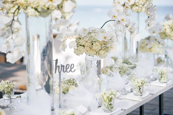 在海滩上装饰着白色兰花 白色玫瑰 白色和清洁主题的招待会餐桌的婚礼场地 — 图库照片