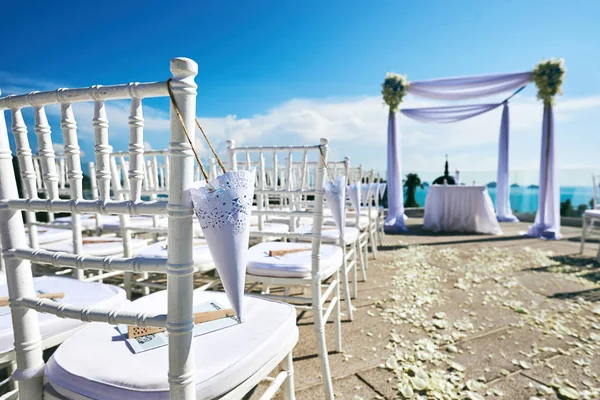 Место проведения свадьбы установка на холме, арки и алтаря украшения, белые стулья с конусом из лепестков розы — стоковое фото