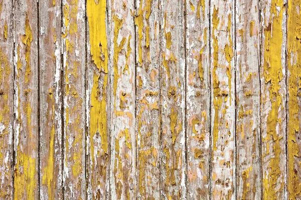 Old wooden wall painted with yellow color peeling revealed rustic texture