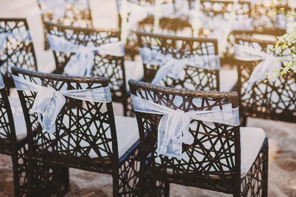 O lado de trás de cadeiras de madeira preta com decoração faixa de organza branca para local de casamento na praia — Fotografia de Stock