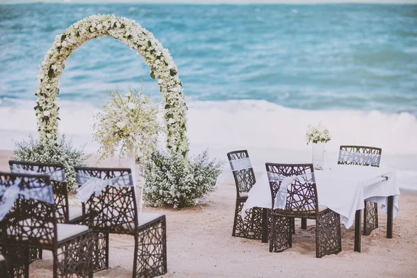 Установка места проведения свадьбы на пляже с цветочным декором на арке, панорамный вид на океан — стоковое фото