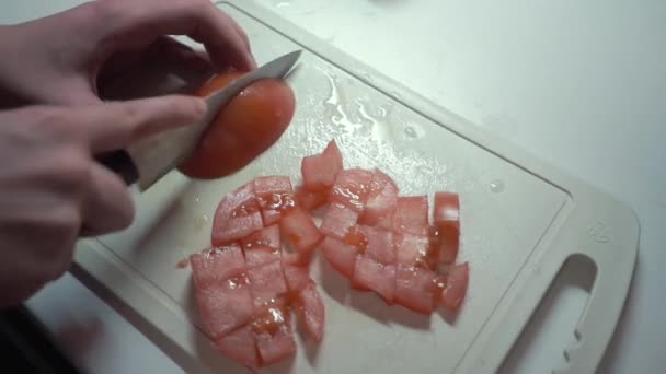 Uma menina corta um tomate com uma faca — Vídeo de Stock