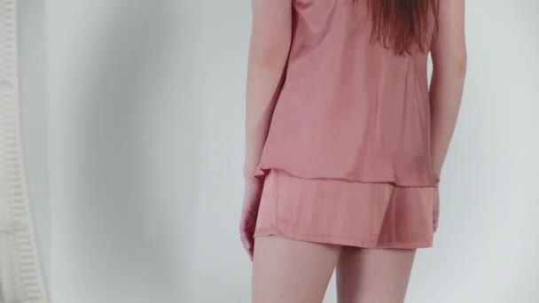 Short rose en gros plan. Fille heureuse dansant devant la caméra, posant en pyjama neuf sur un fond blanc .
