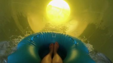 Mavi kauçuk bir halkanın üzerindeki su parkındaki sarı bir su kayağından indim. Genç bir kızın ayaklarının birinci şahıs görüntüsü. Su arıtma tesiste eğlence..