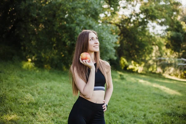 sports girl eating an apple in the park