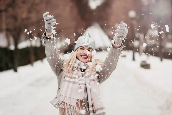 beautiful girl throws snow in a winter park