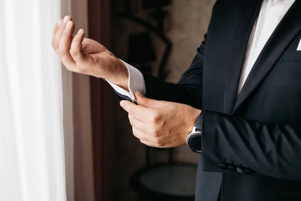 man straightens shirt and jacket sleeve