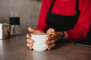 Barista elinde bir fincan kahve tutuyor.