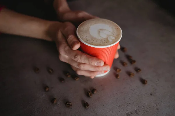 takeaway coffee in a red paper cup and with coffee grains
