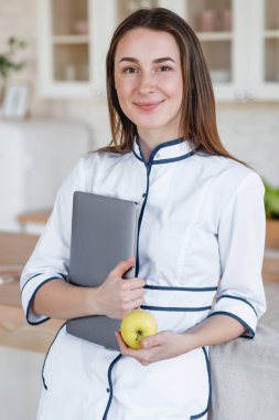 Laptop ve elma tutan beslenme uzmanı bir kız.
