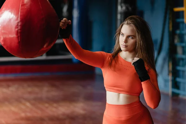 Sporty girl in boxing bandages near a punching bag