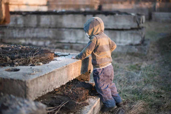 A criança joga-se por seixos em velhas chapas de concreto — Fotografia de Stock