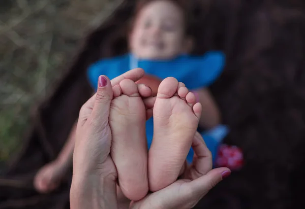 Kleine vingers van kleine baby benen in warme moederlijke handen. Rechtenvrije Stockafbeeldingen