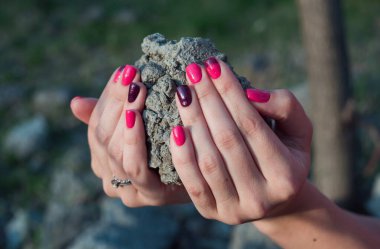 Parlak manikürlü güzel elli kız. Moda ve güzellik dünyası. Kadınların elindeki bir kaldırım taşı