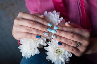 Modern bir kızın güzel bahar manikürü. Beyaz çiçekler ve kadınların elleri. Çivi endüstrisi.