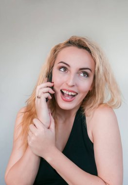 Bir kadın telefonda konuşurken güler. Kahverengi gözlü sarışın. Telefon görüşmesi. Akıllı telefondan konuşan kız..