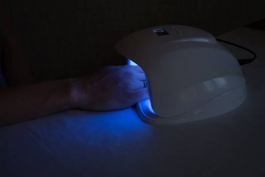 Manikür için mavi lamba. Çivilerin üzerindeki kabuğu kurutmak. Manikür yapmak için beyaz bir lamba. Güzellik ve Moda Konsepti