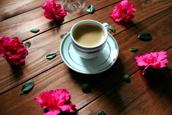 Coffee with flowers on the wooden table.