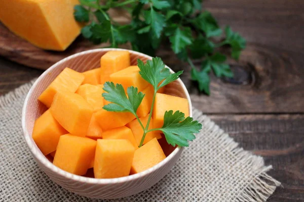 Ahşap zemin üzerine doğranmış kabak ile ahşap kase. Vejetaryen ve vegan gıda.