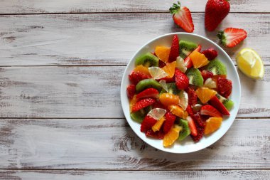 Sağlıklı taze meyve salatası ahşap arka plan üzerinde saçtan. Üstten Görünüm.