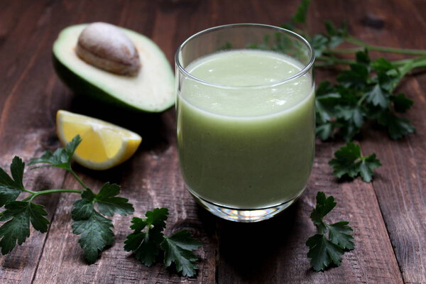 Healthy green smoothie with avocado on the wooden background. Top view.