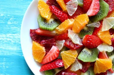 Sağlıklı taze meyve salatası ahşap arka plan üzerinde saçtan. Üstten Görünüm.