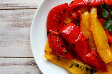 Kavrulmuş sarı ve kırmızı biber beyaz bir tabak içinde. Vejetaryen ve vegan gıda. Üstten Görünüm.