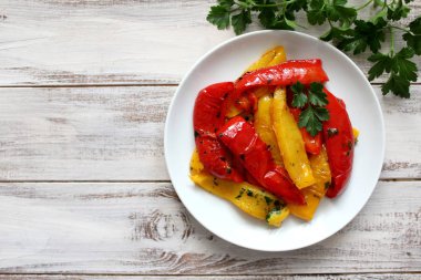 Kavrulmuş sarı ve kırmızı biber beyaz bir tabak içinde. Vejetaryen ve vegan gıda. Üstten Görünüm.