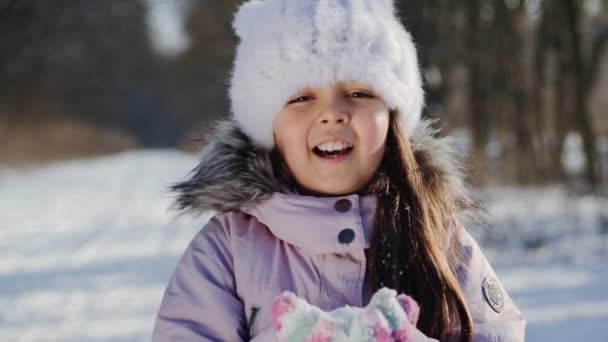 Uma menina de dez anos a soprar neve. Movimento lento — Vídeo de Stock